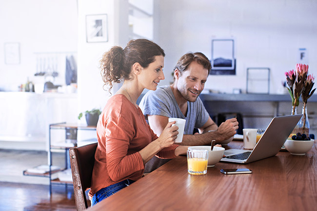Couple sitting down on a chair looking into their laptop