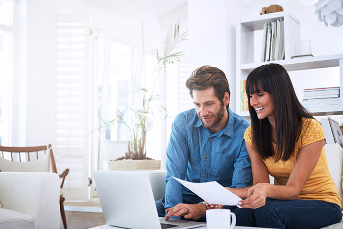 Couple using the laptop and smiling.