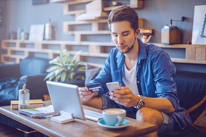 Guy looking at his card and phone while sitting on the couch.